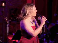 a woman in a red dress sings into a microphone