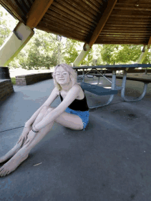 a girl sits on the ground under a pavilion