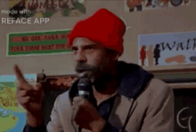 a man wearing a red hat is speaking into a microphone and pointing