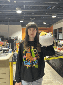 a girl in a scooby doo shirt holds a stuffed animal