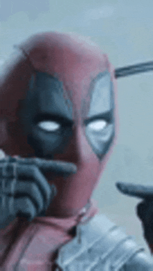 a close up of a deadpool holding a gun and pointing at something .