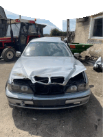 a silver car with a bmw logo on the front is parked in a dirt lot