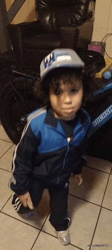 a young boy wearing a blue jacket and a hat is standing in front of a bicycle with the word krush on it