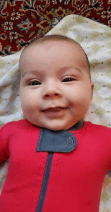 a baby wearing a red outfit is smiling for the camera