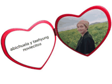 a red heart shaped mirror with a picture of a man in a field