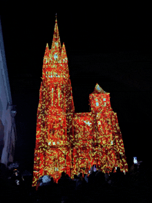 a large building is lit up at night with a projection of a christmas tree on it