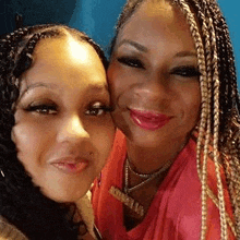 two women are posing for a picture together and smiling . one of the women has braids in her hair .