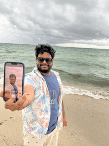 a man is holding up a cell phone with a picture of himself on it