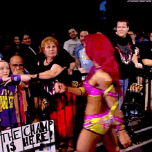 a woman in a pink and yellow outfit is standing in front of a sign that says the champ is here