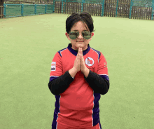 a young boy wearing sunglasses and a red shirt that says ' aok ' on the front