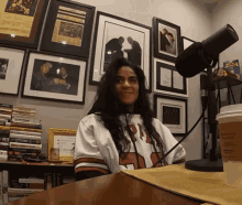 a woman sitting at a table with a microphone and a cup of coffee