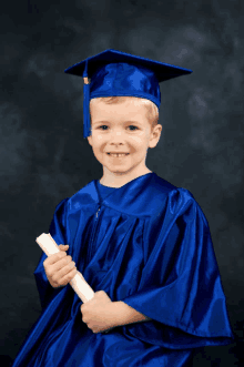 a young boy wearing a blue graduation cap and gown holds a diploma