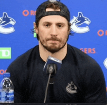 a man speaking into a microphone in front of a blue background that says rogers