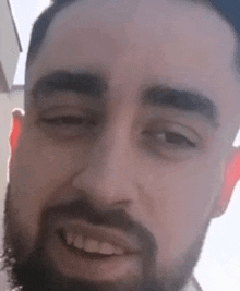 a close up of a man 's face with a beard smiling .