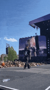 a man in a black shirt with a skull on it walks on a stage in front of a crowd