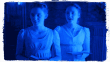 two women in white dresses are standing next to each other in a dark room