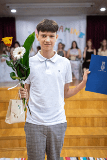 a boy in a white shirt holds a bouquet of flowers and a certificate