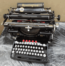 a black remington typewriter with red keys sits on a table