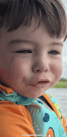 a close up of a child 's face wearing an orange shirt