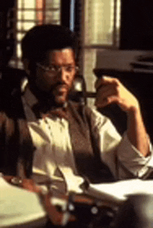 a man in a suit and tie is sitting at a desk with a pen in his hand .