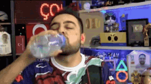 a man is drinking water from a bottle in front of a sign that says " co "