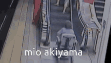 a person in a wheelchair is riding an escalator and the words mio akiyama are on the screen