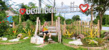 a woman is sitting on a wooden bench in front of a sign that says ' aoomnoo '