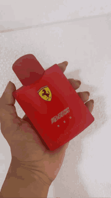 a person holding a bottle of ferrari red perfume