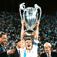 a man holds up a trophy that says champions league on it