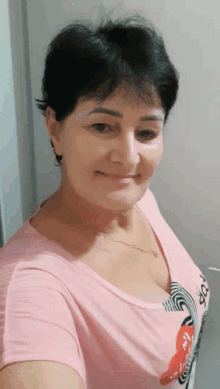 a woman in a pink shirt is taking a selfie and smiling .