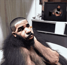 a man with a beard is sitting in front of a television