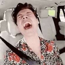 a man is laughing in the back seat of a car .