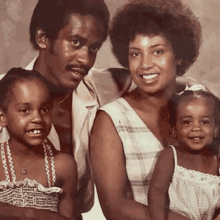 a man , woman , and two children are posing for a picture together .