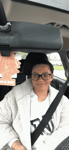 a woman in a car with a coral reef air freshener