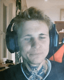 a man with a tattoo on his neck is wearing headphones and smiling