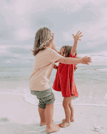 a boy and a girl are dancing on the beach