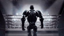 a robot is standing in a boxing ring looking at the audience