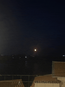 a full moon is visible in the night sky over a body of water