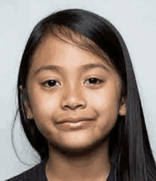 a close up of a young girl 's face with long black hair .