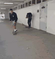 a man riding a skateboard in a hallway with a sign on the wall that says " no smoking "