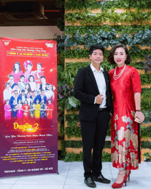 a man and woman standing in front of a sign that says duyen 2