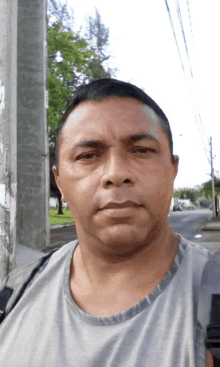 a man in a grey shirt is standing in front of a pole