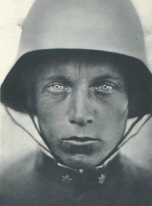 a black and white photo of a man wearing a helmet with a serious look on his face