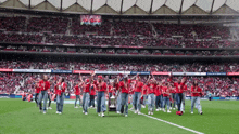 a group of people walking on a soccer field with a trophy in front of a stadium that says copa del rey 2021