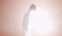 a man in a white shirt is standing in front of a pink background with a light coming out of his head .