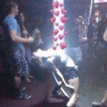 a group of people are dancing in a club with hearts coming out of a pole .