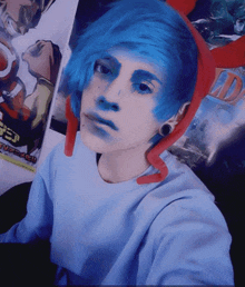 a person with blue hair is taking a selfie in front of a poster that says ' tokyo ghoul ' on it