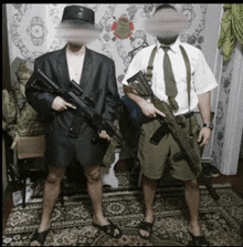 two men standing next to each other holding guns in front of a wall with a sticker on it