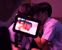 a couple of boys kissing in front of a camera with kinnbig tumblr written below them
