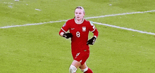 two women are playing soccer on a field and one of them is wearing a red jersey with the number 8 on it .